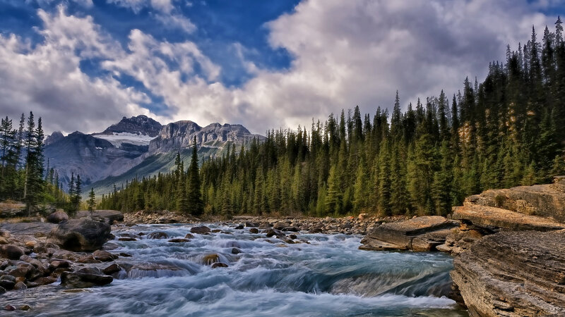 River Flowing Through Forest — Blue, Dramatic, Afternoon, Photograph, Mountains, Trees