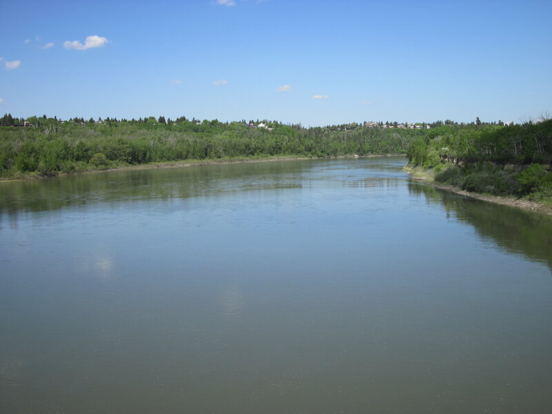 River Flowing Through Forest — Blue, Serene, Afternoon, Photograph, Trees, Sky, Houses