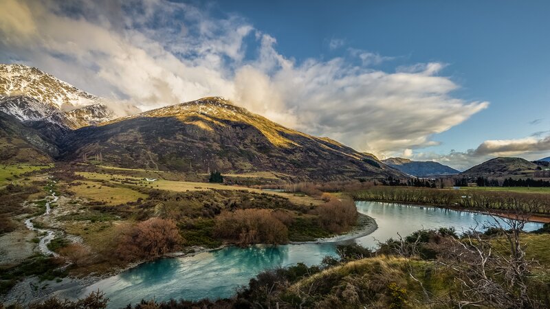 River Flowing Through Valley — Blue, Dramatic, Afternoon, Photograph, Mountains, Clouds