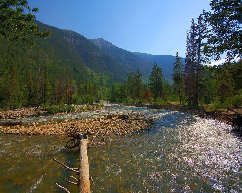 River Flowing Through Valley — Blue, Serene, Afternoon, Photograph, Mountains, Trees, Rocks, Green