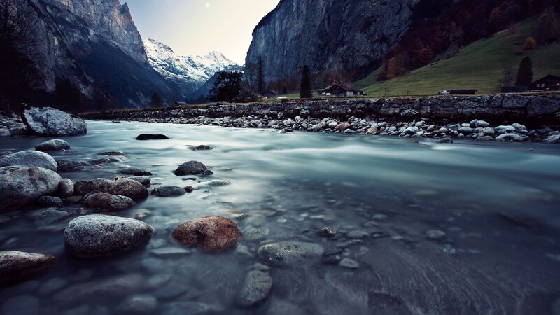 River Flowing Through Valley — Blue, Serene, Morning, Photograph, Mountains, Rocks, Huts