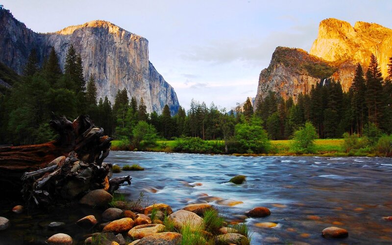 River Flowing Through Valley — Blue, Serene, Sunset, Photograph, Mountains, Trees, Driftwood