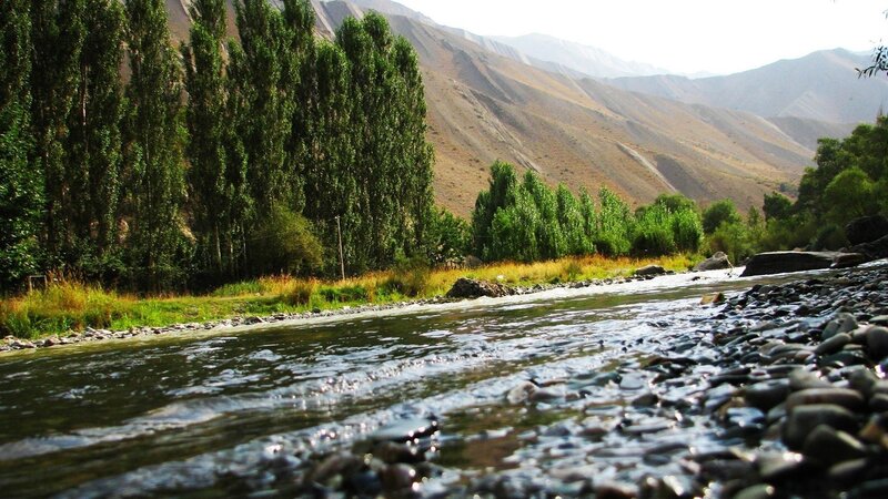 River Flowing Through Valley — Green, Serene, Afternoon, Photograph, Trees, Mountains, Rocks, Brown
