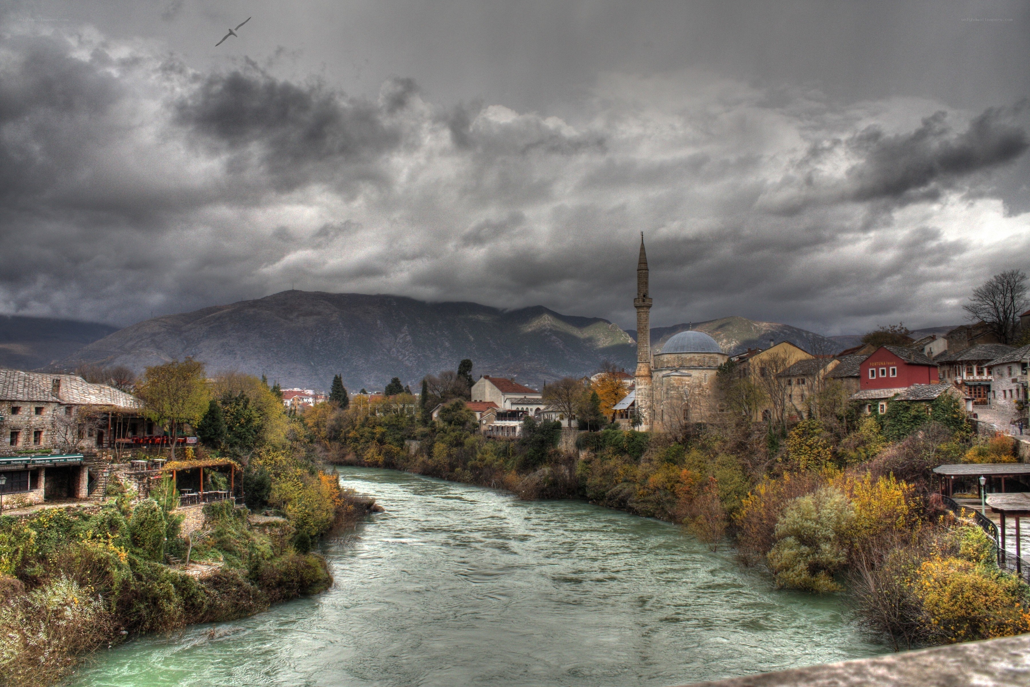 River town with mosque under stormy sky