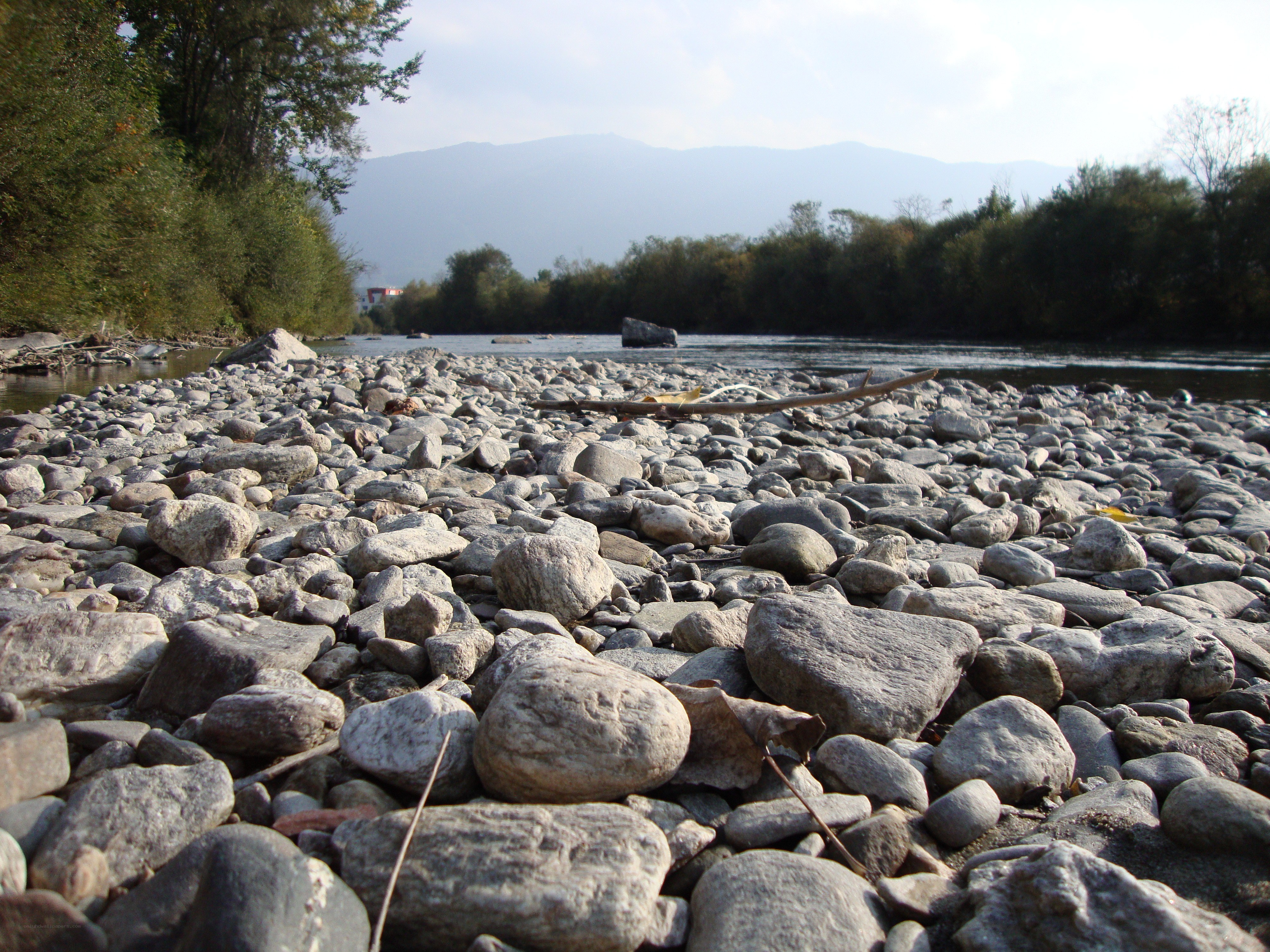 Riverbank with pebbles and mountains