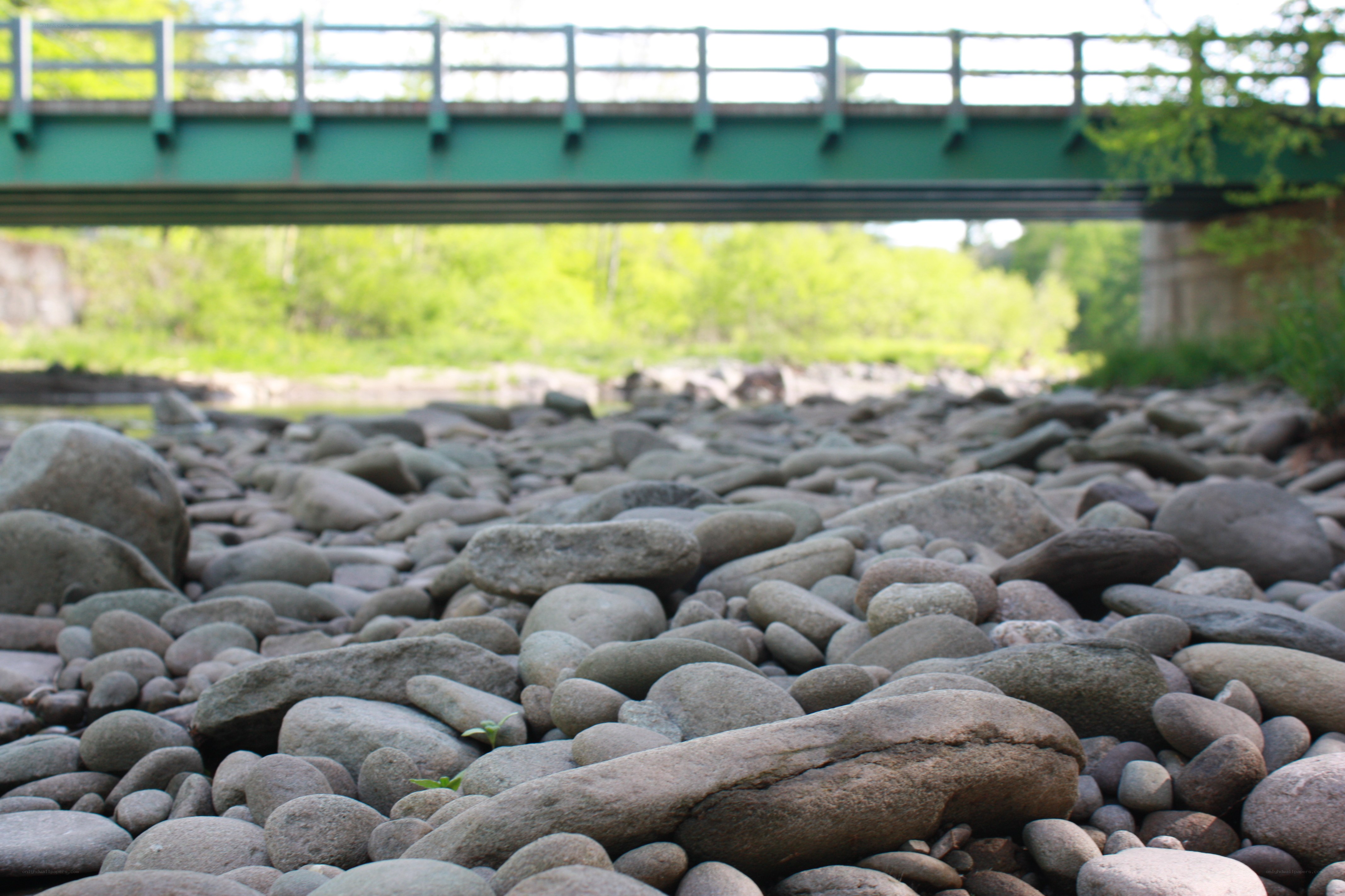 Riverbed under a green bridge