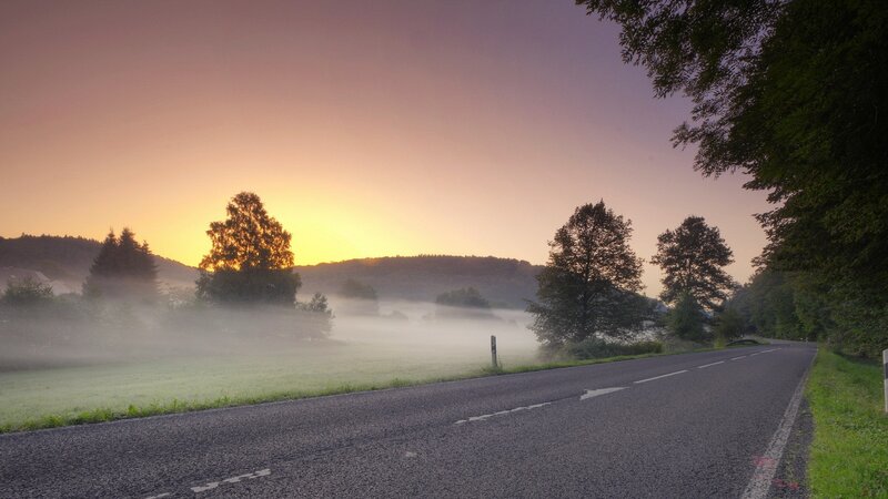 Road at sunrise with morning mist
