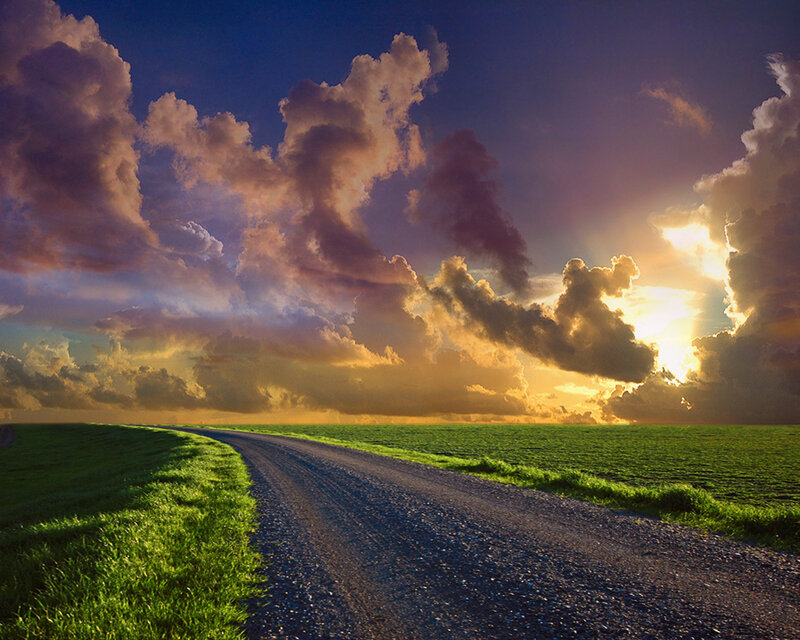 Road at sunset over green fields