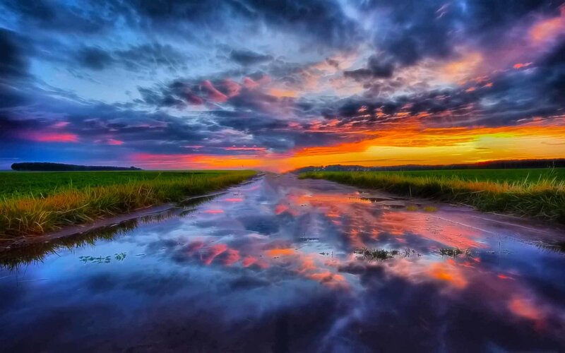 Road at sunset with sky reflection