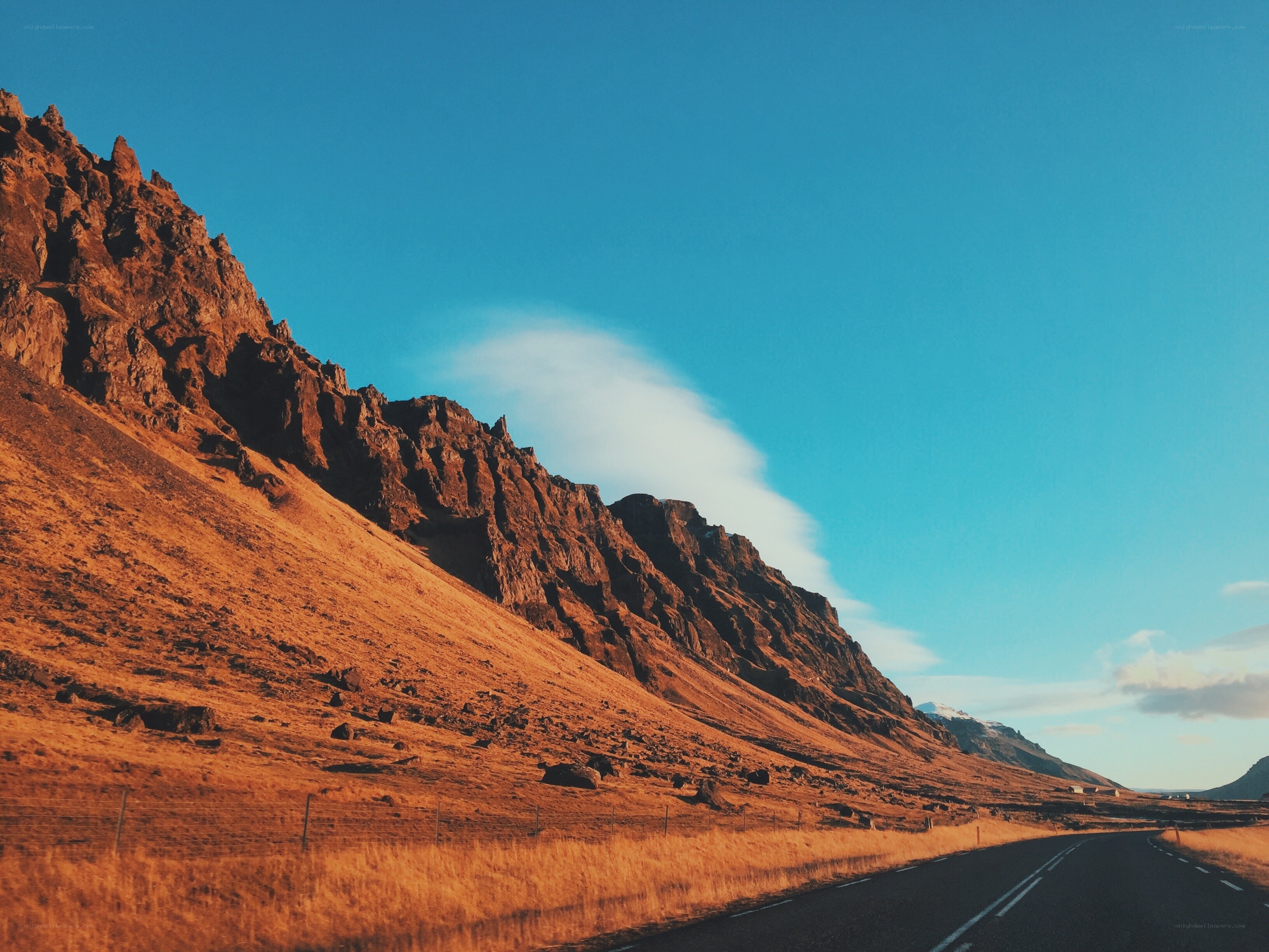 Road beside mountain under blue sky