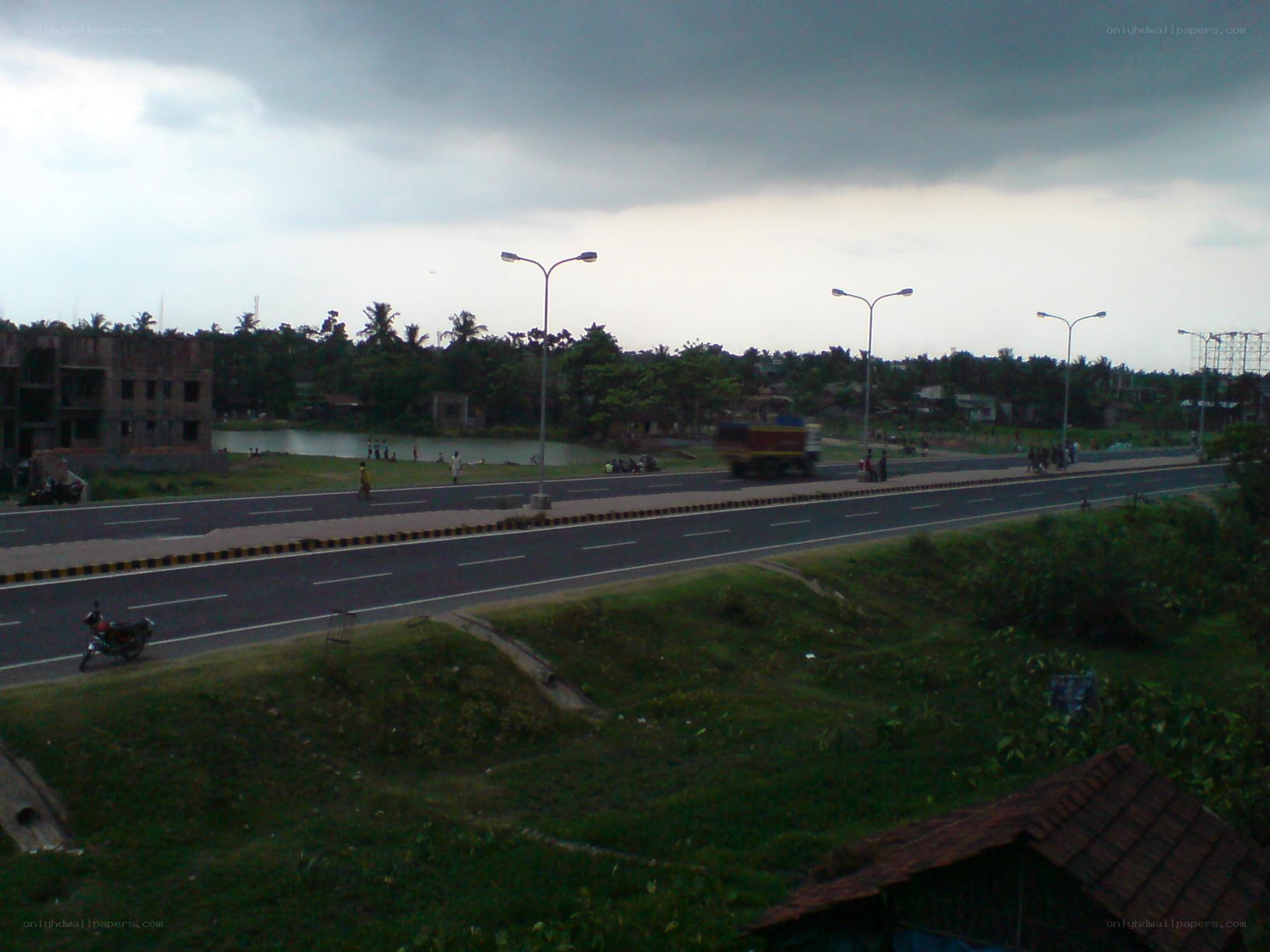 Road near pond with overcast sky