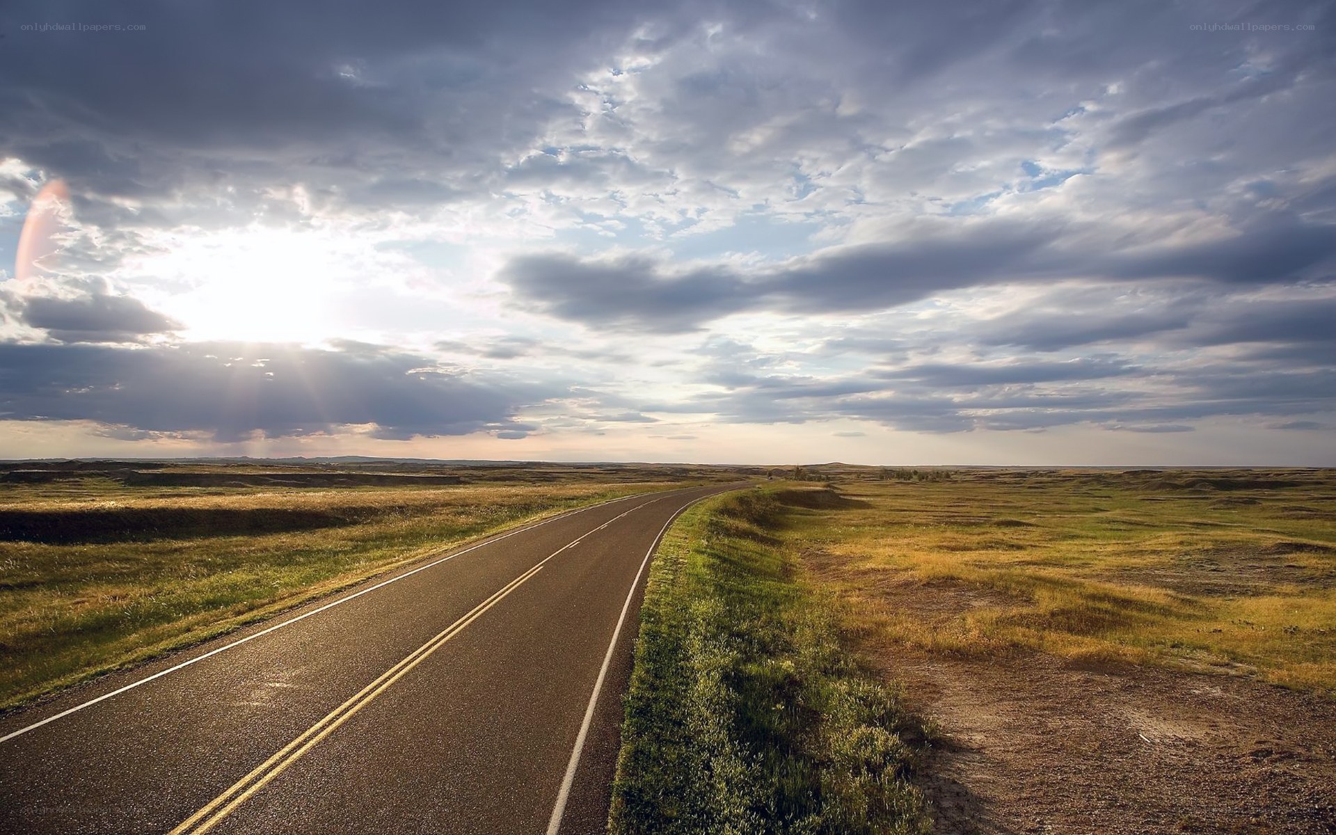 Road through open plains at sunset