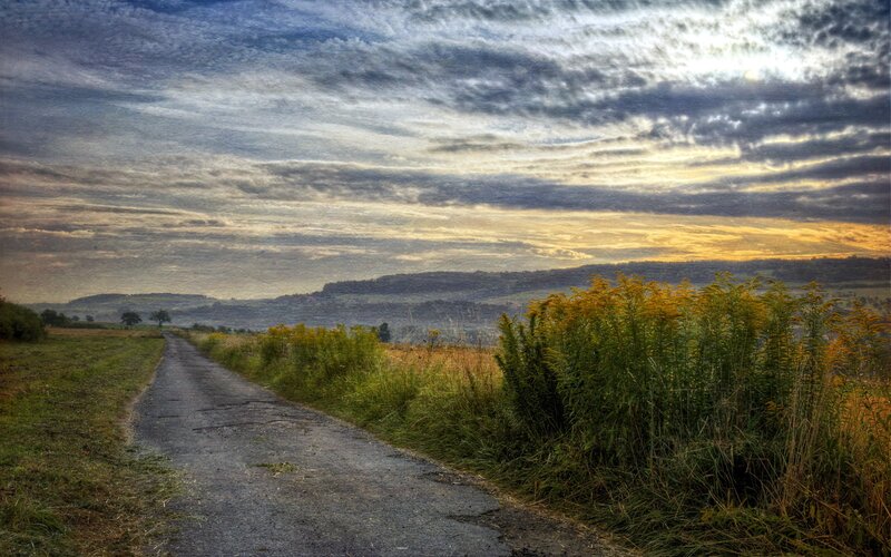 Road through rural landscape at sunset