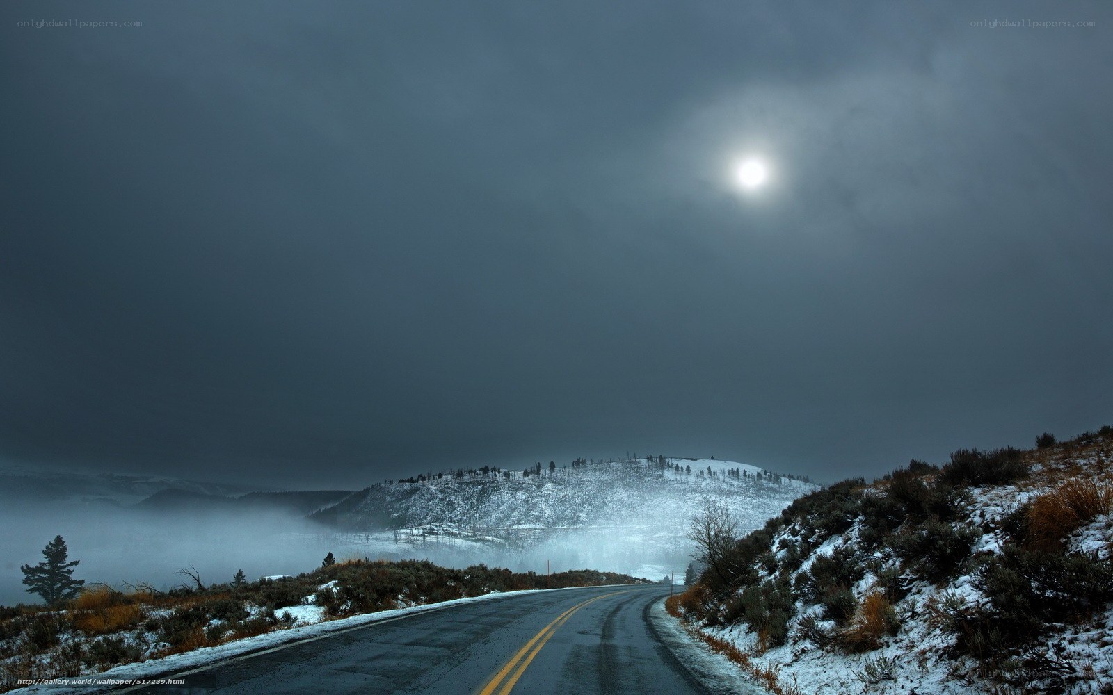 Road through snowy mountains at night