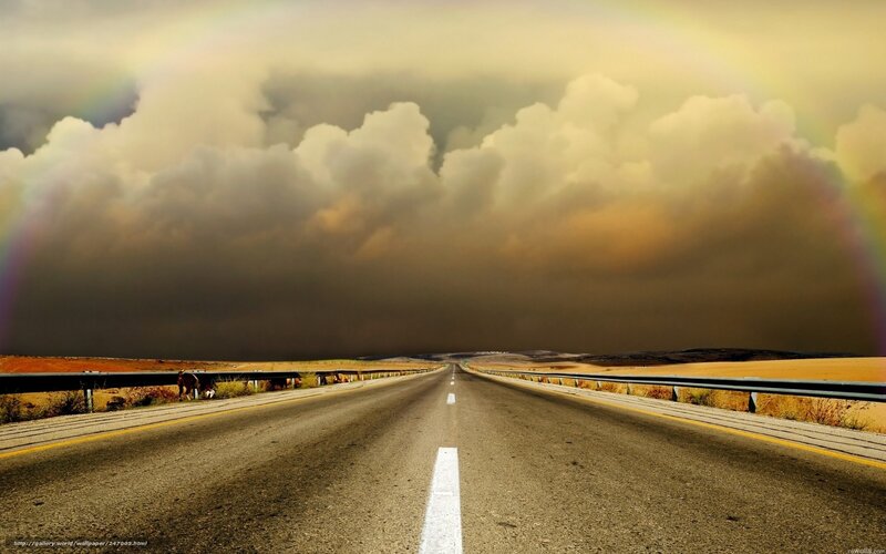 Road under stormy sky with rainbow