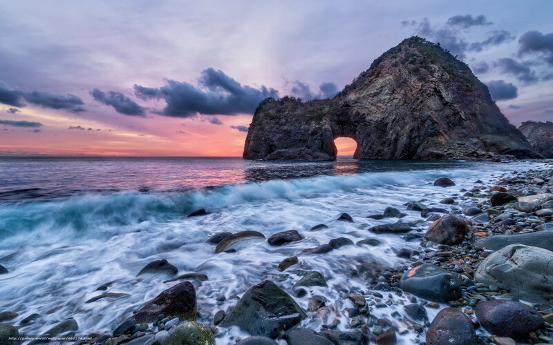 Rock arch at sunset on rocky shore