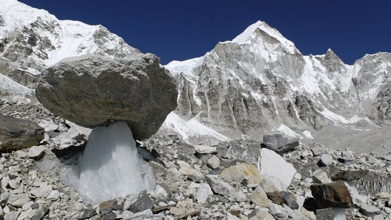 Rock balancing on ice in mountain valley
