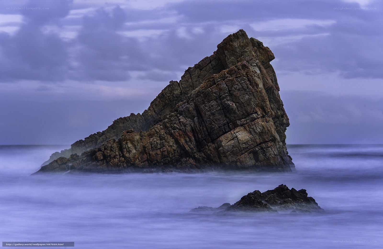 Rock formation in ocean at dusk
