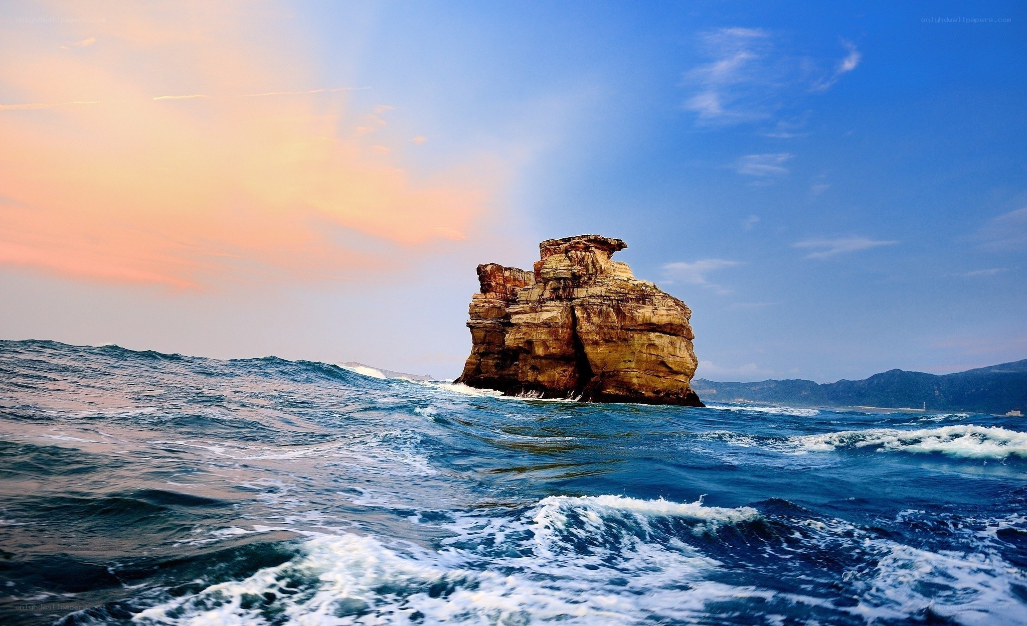 Rock formation in ocean at sunset