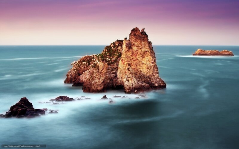 Rock formations in ocean at sunset