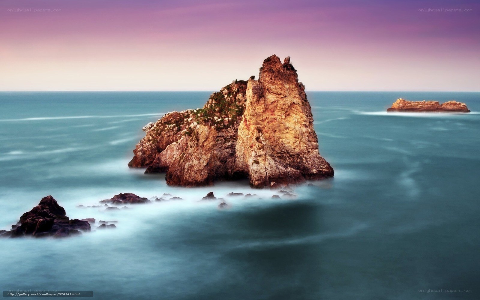 Rock formations in ocean at sunset