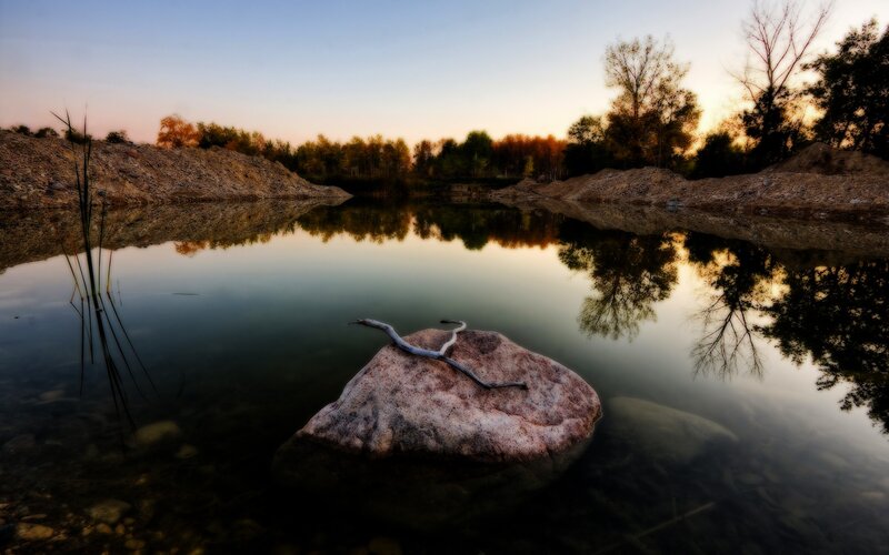 Rock in a calm lake at sunset