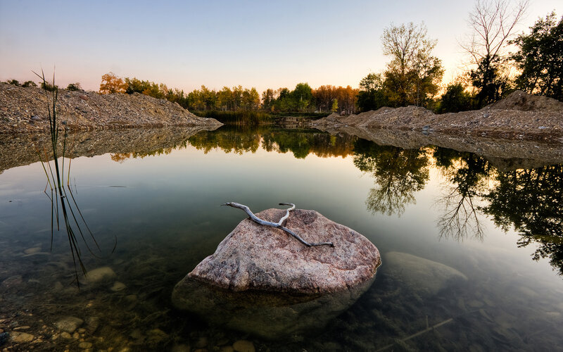 Rock in a calm pond at sunset