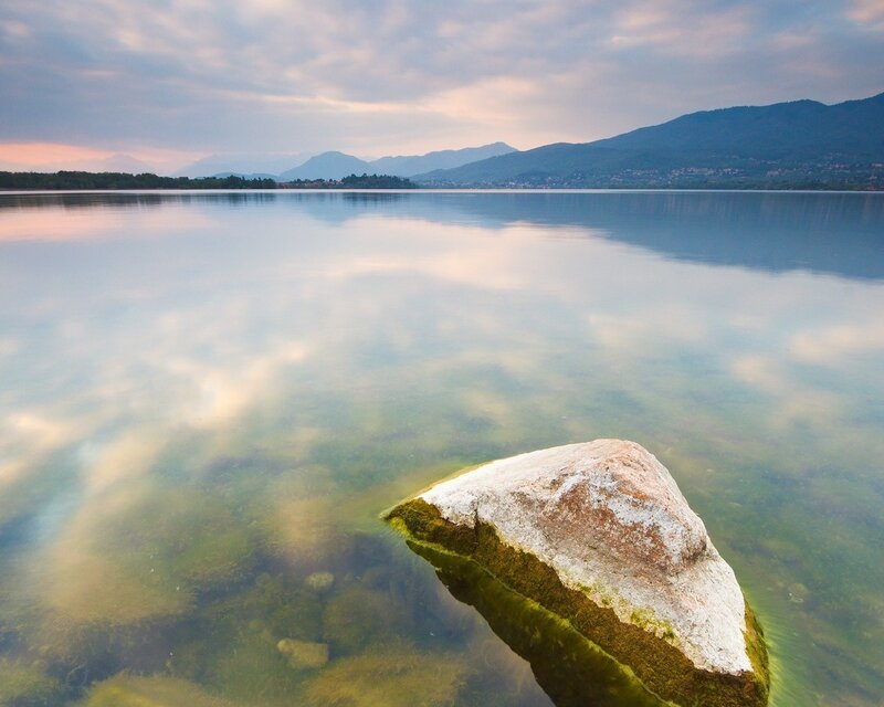 Rock in calm lake at sunset