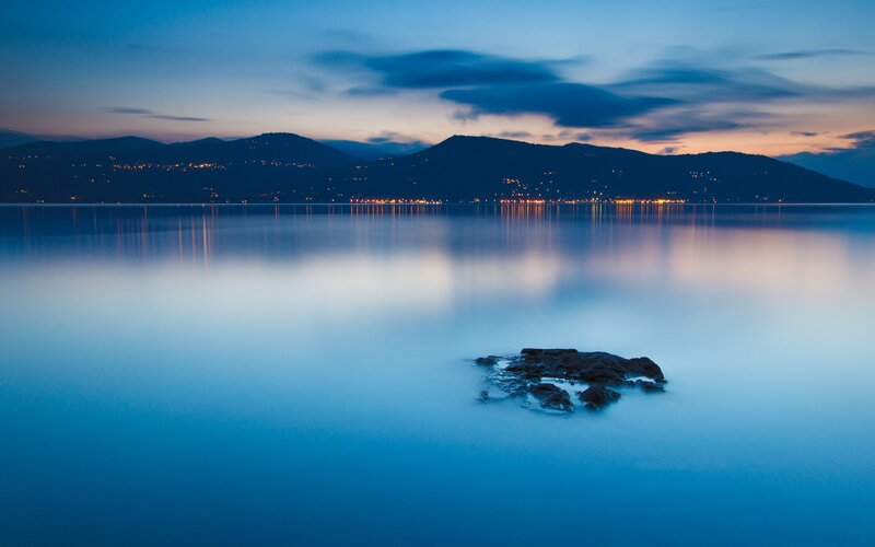 Rock in Calm Water — Blue, Serene, Night, Photograph, Mountains, Lights