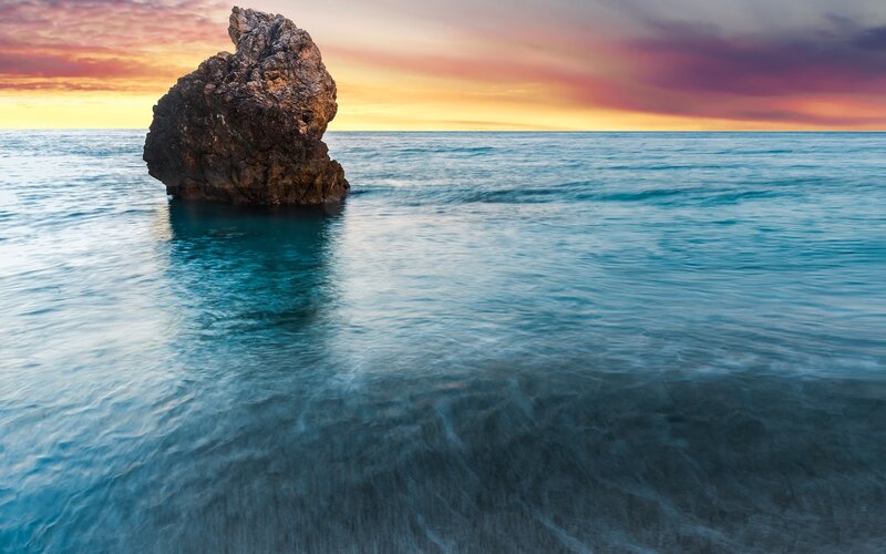 Rock in the ocean at sunset