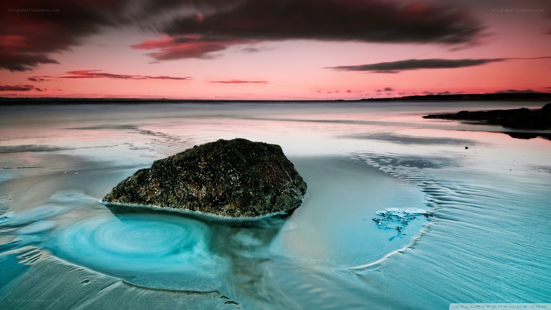 Rock on beach at sunset