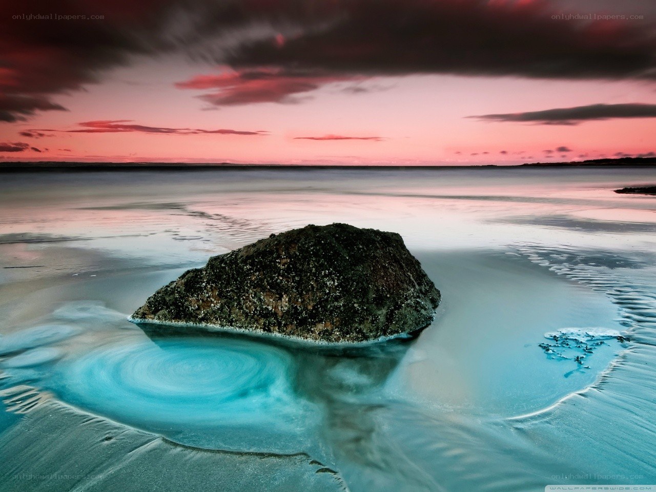 Rock on beach at sunset
