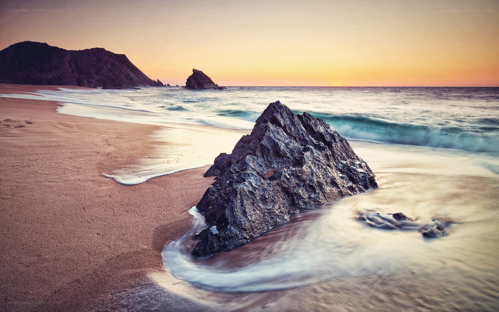 Rock on the beach at sunset