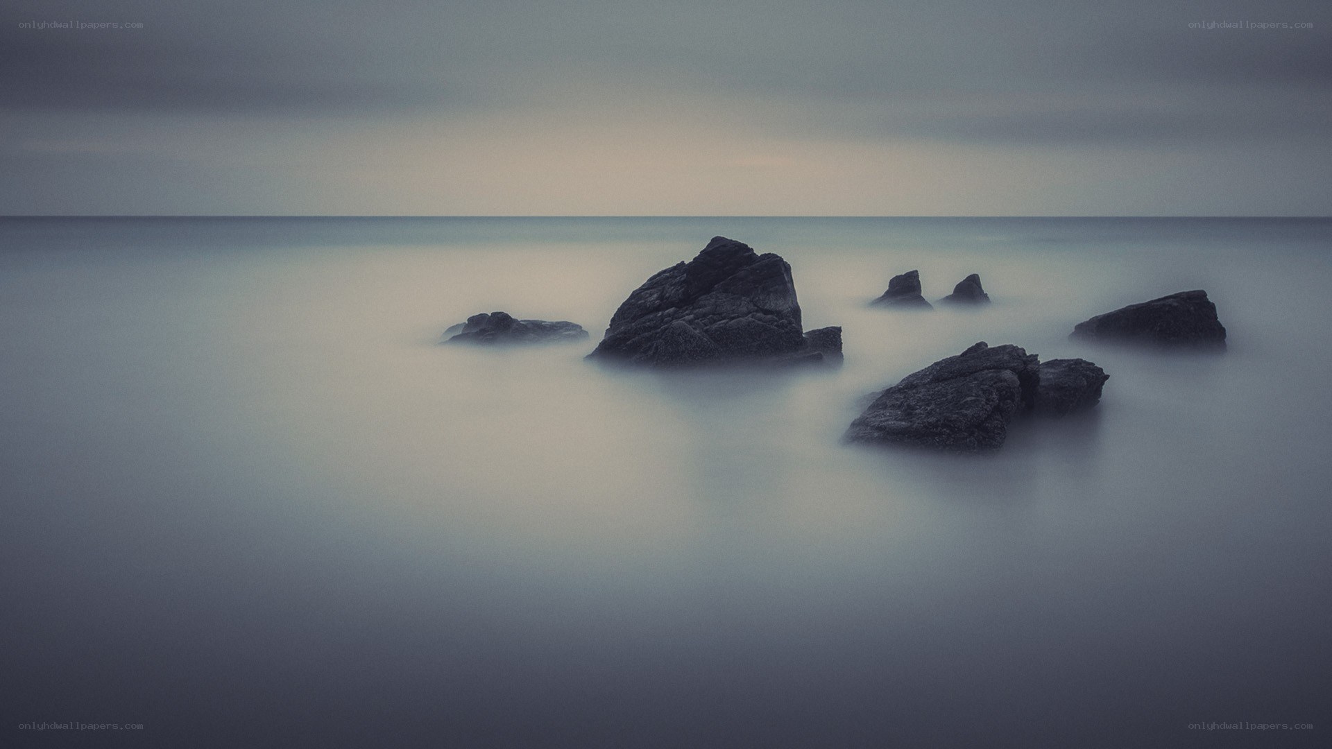 Rocks in calm sea at dusk