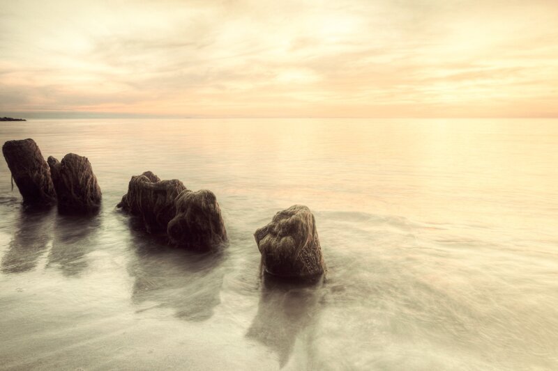 rocks in calm sea at sunset