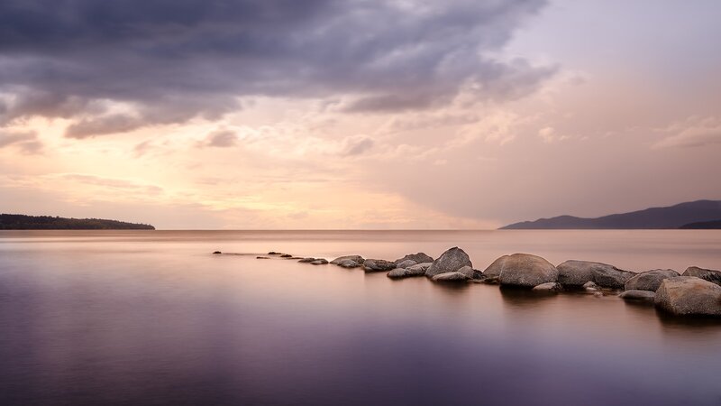 Rocks in Calm Water — Purple, Serene, Sunset, Photograph, Clouds, Mountains