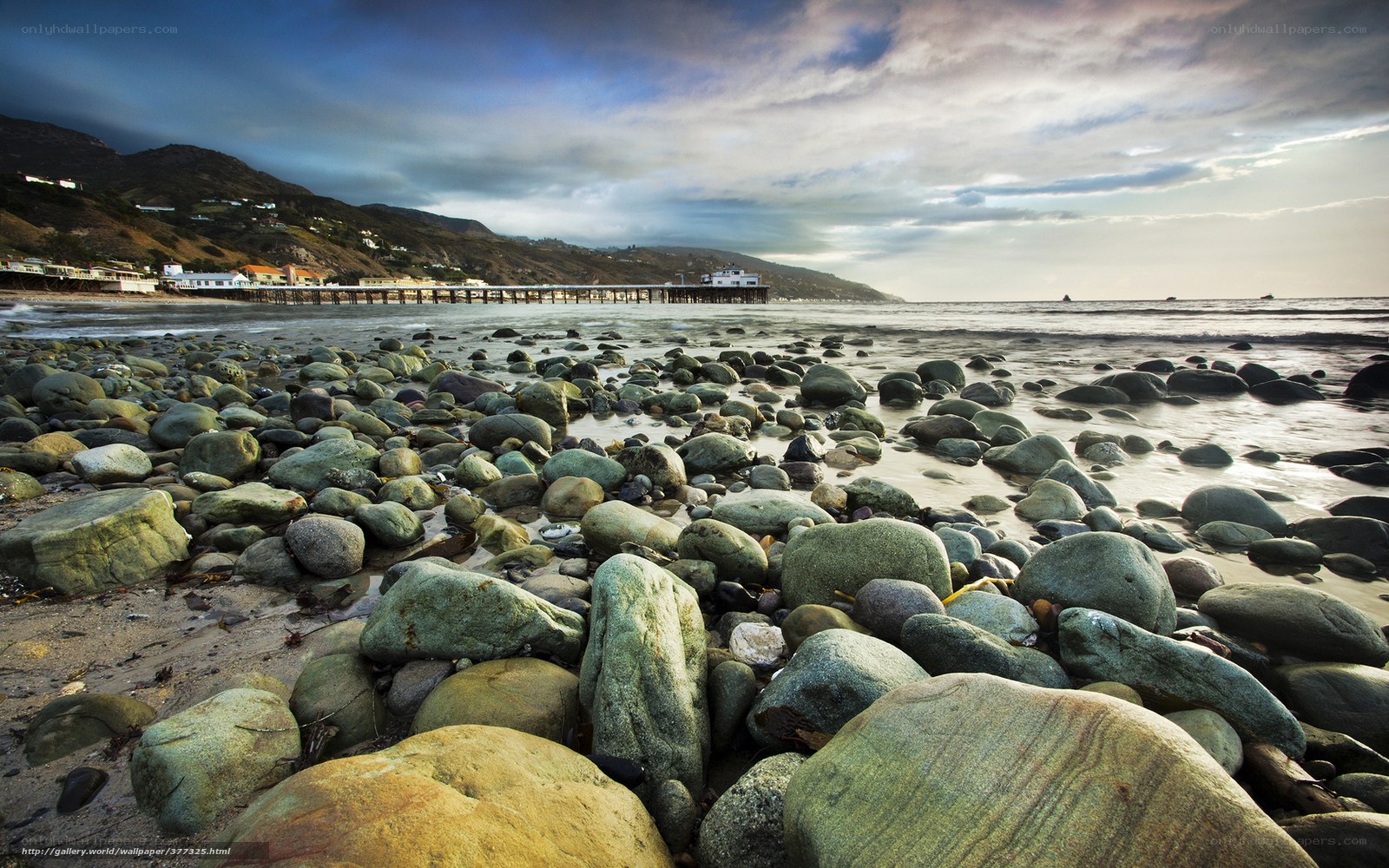 Rocky beach with pier at sunset