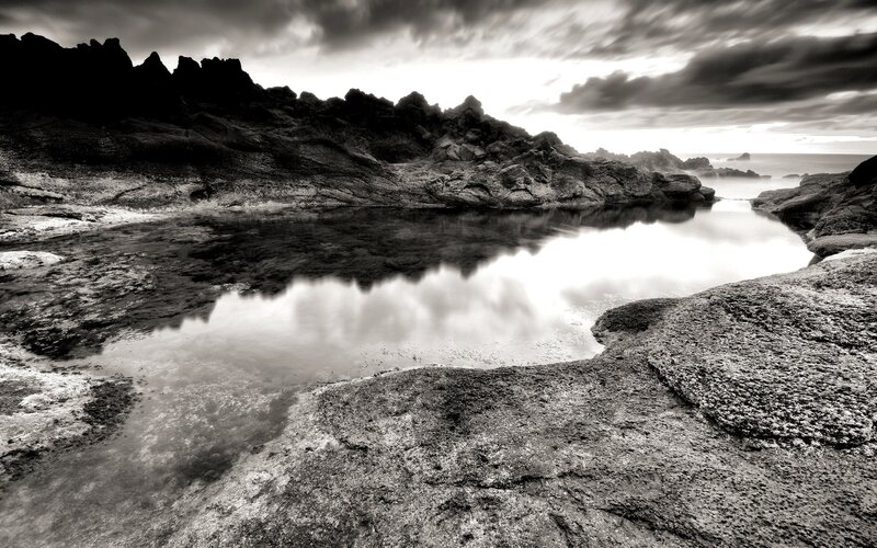 Rocky coastal pool under cloudy sky