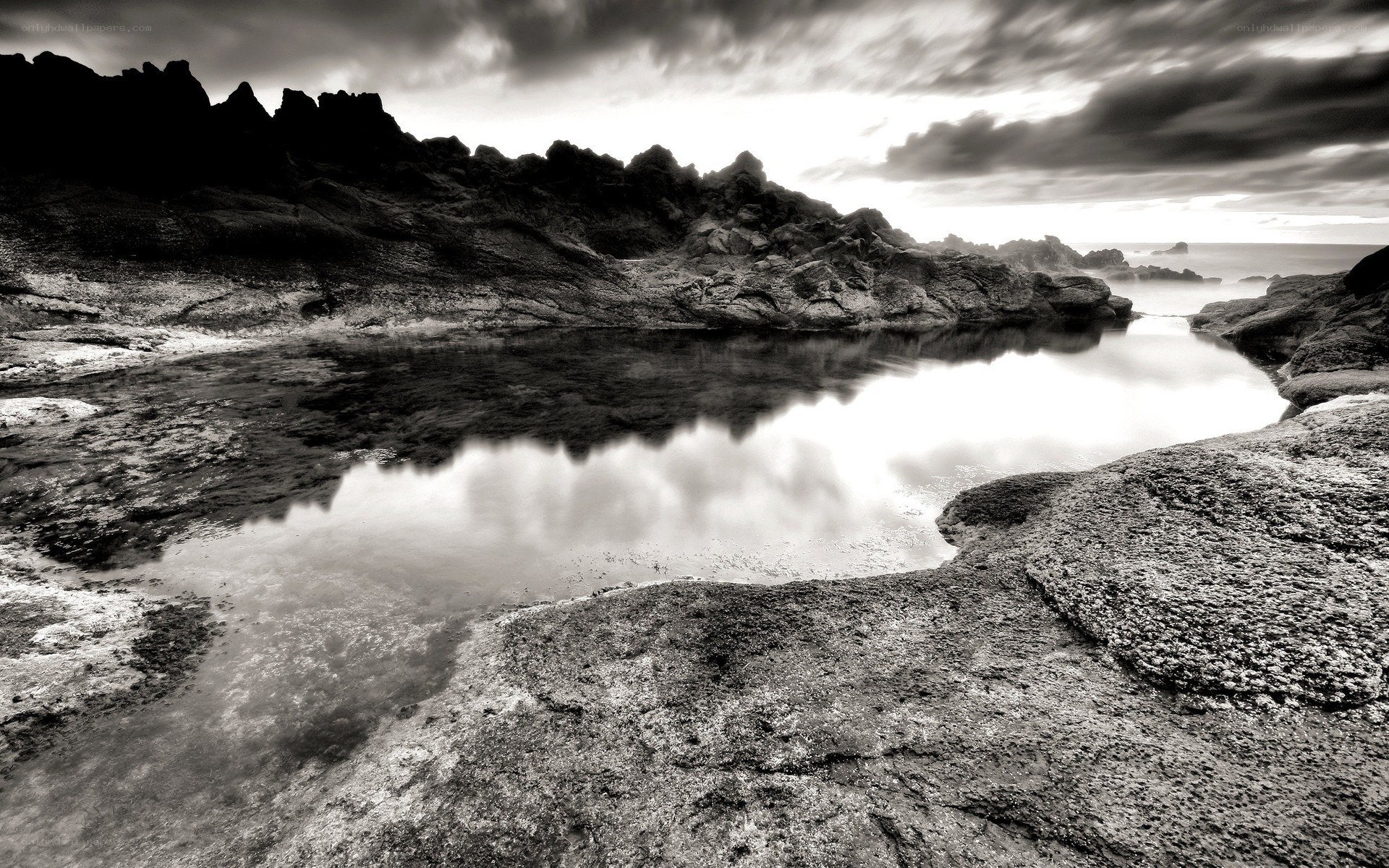 Rocky coastal pool under cloudy sky
