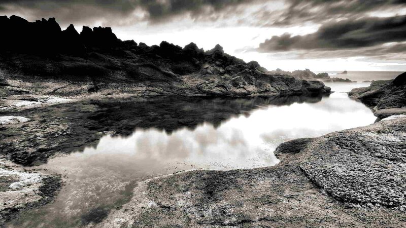 Rocky coastal pool under storm clouds