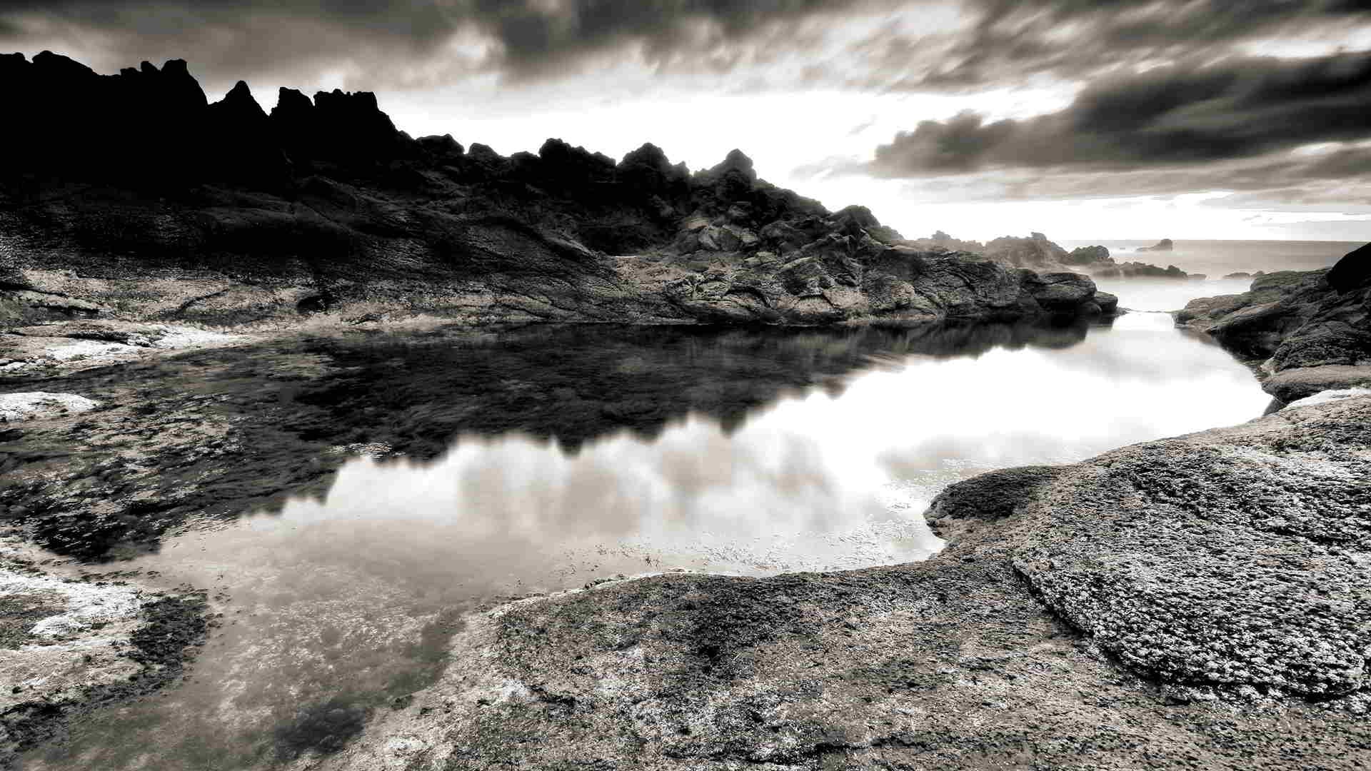 Rocky coastal pool under storm clouds