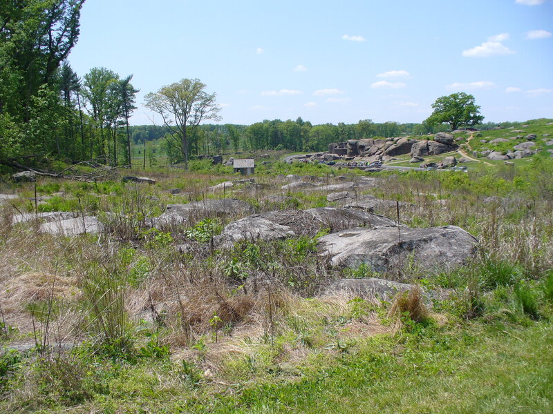 rocky field with trees and a small building