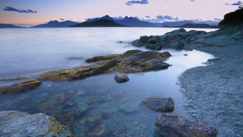 Rocky shore at dusk with mountains