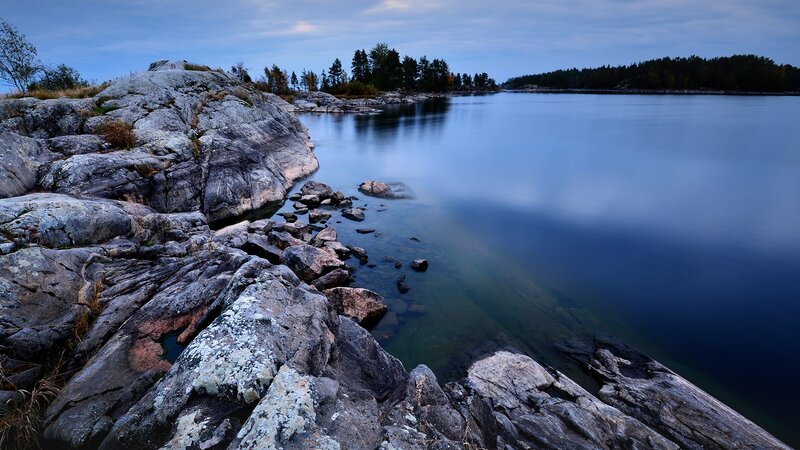 Rocky Shoreline at Dusk — Blue, Serene, Photograph, Rocks, Water, Trees