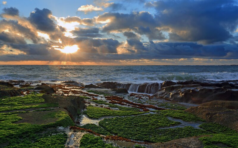 Rocky Shoreline at Sunset — Blue, Dramatic, Photograph, Ocean, Clouds, Sun