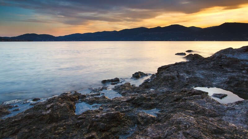 Rocky Shoreline at Sunset — Blue, Serene, Photograph, Sea, Mountains
