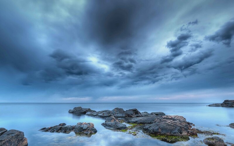 Rocky Shoreline under Storm Clouds — Blue