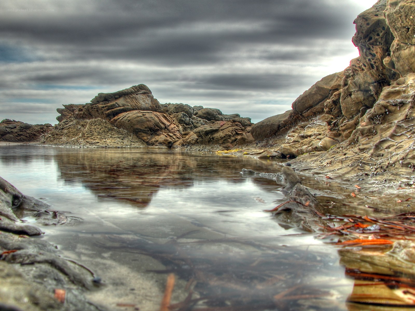 rocky tide pool under cloudy sky