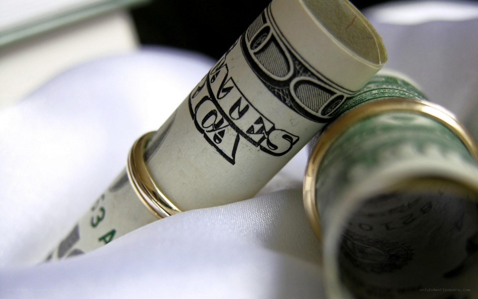 rolled money with wedding rings
