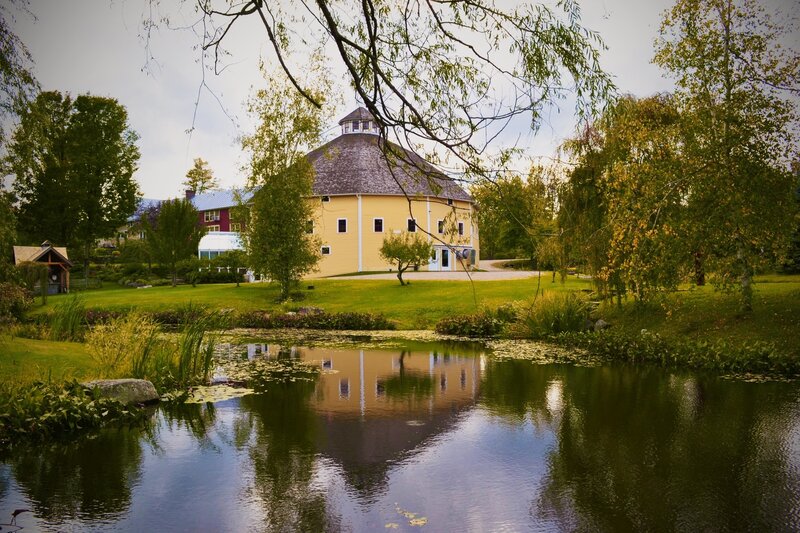 Round yellow barn by a pond